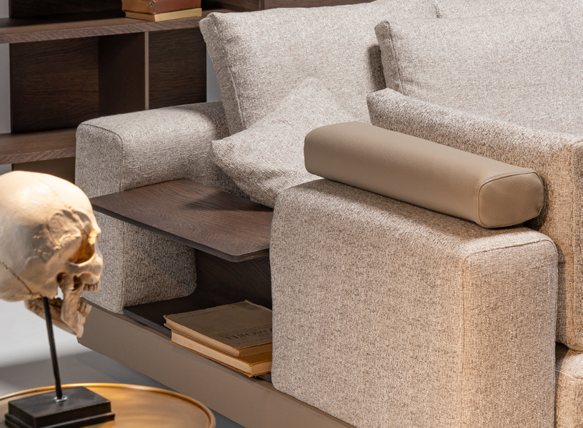 Living space showcasing neutral corner sofa and tall wooden shelving unit.