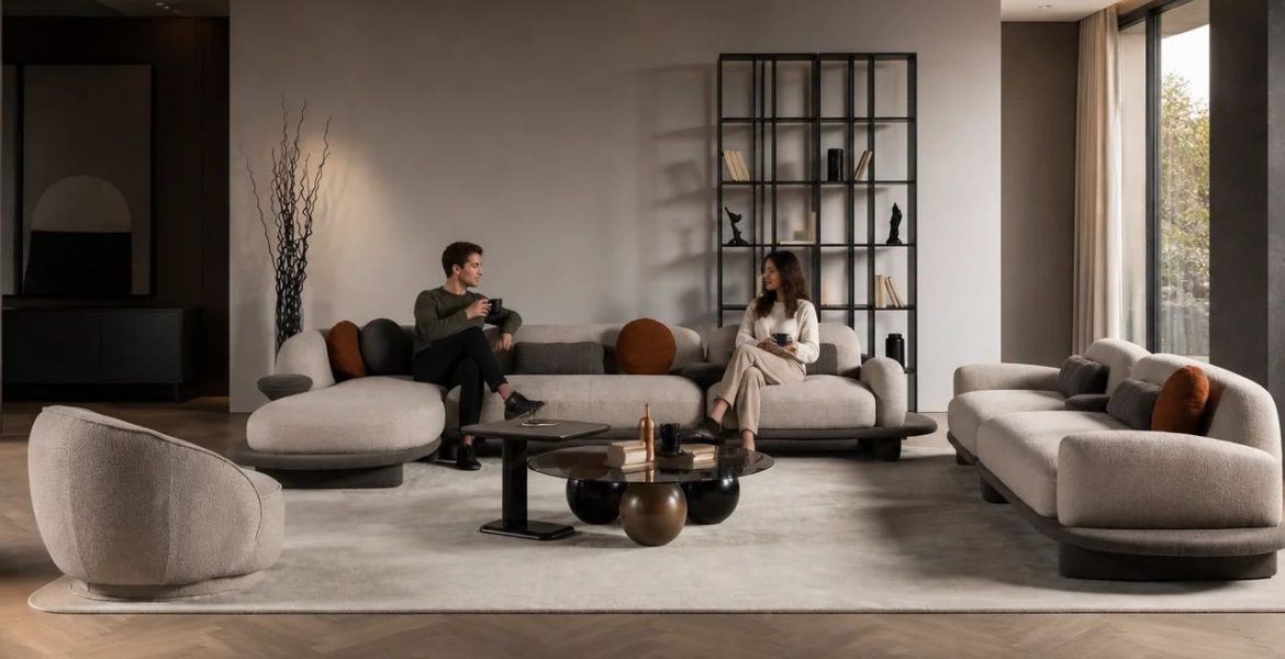 Light‑beige curved corner sofa set with accent pillows, modern coffee tables, open shelving, warm lighting, and a large window overlooking greenery.