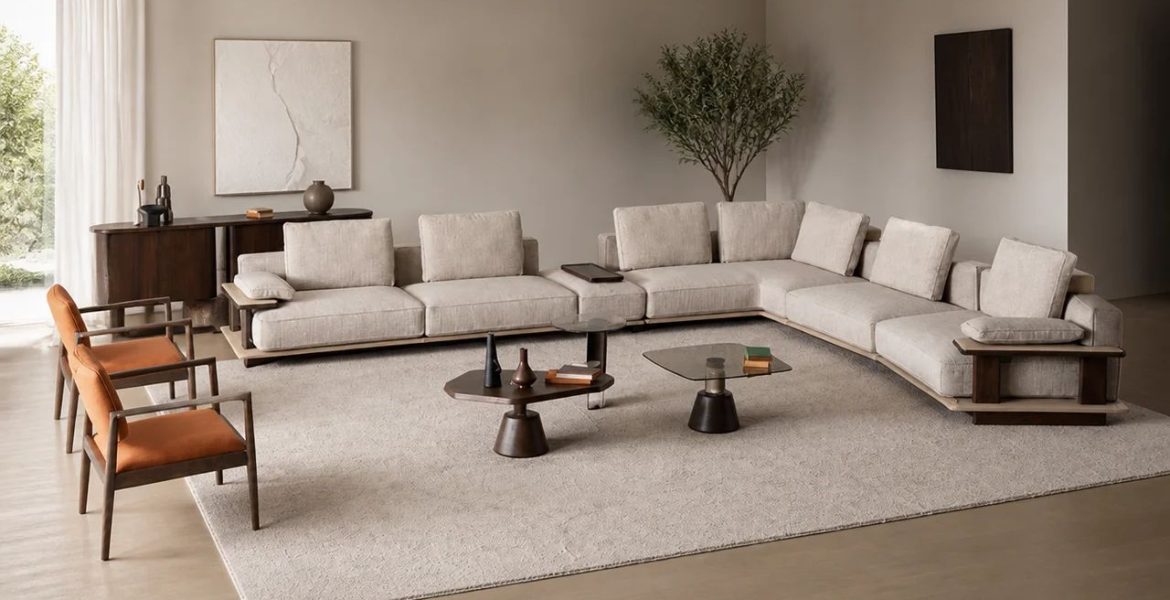 Light‑beige L‑shaped corner sofa with wooden base, dark wood coffee tables, orange‑cushioned armchairs, and minimalist décor in a modern living ro