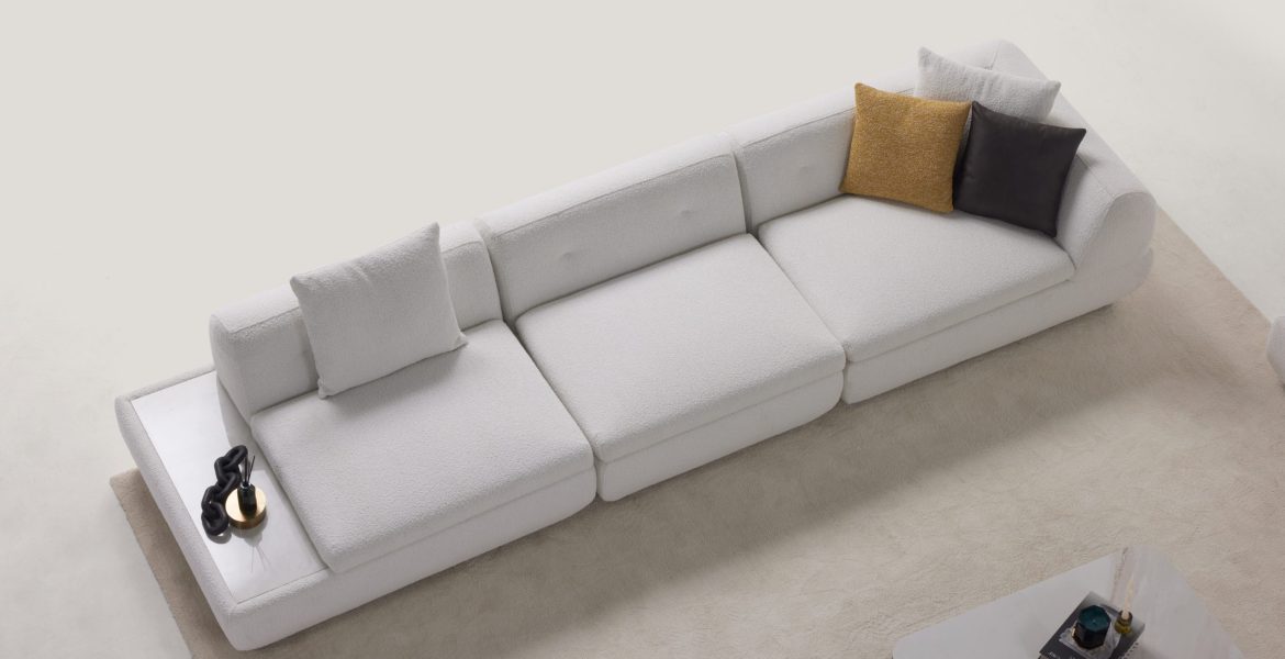 Elegant interior with white corner sofa and bonsai‑style indoor plant.