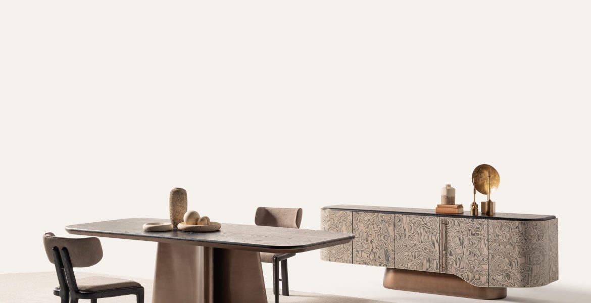 Modern dining table with bronze sculptural base and upholstered chairs.