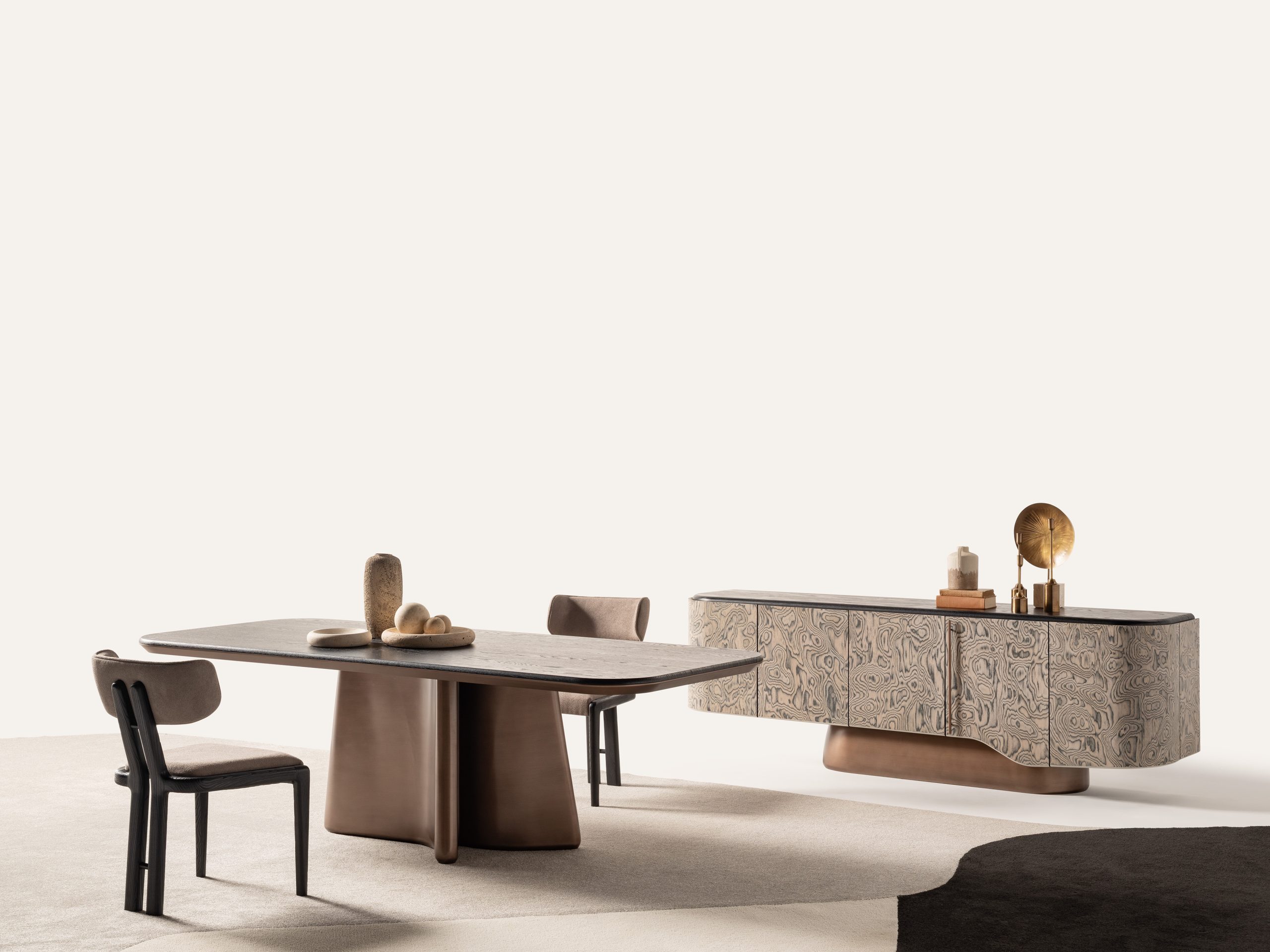 Modern dining table with bronze sculptural base and upholstered chairs.